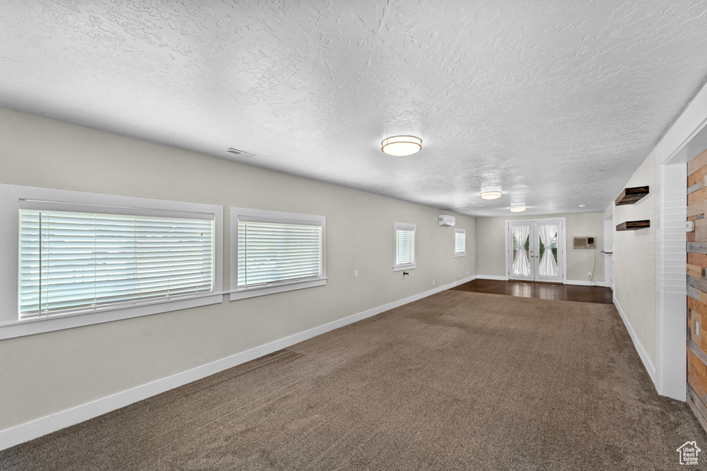 Unfurnished room featuring dark carpet and a textured ceiling