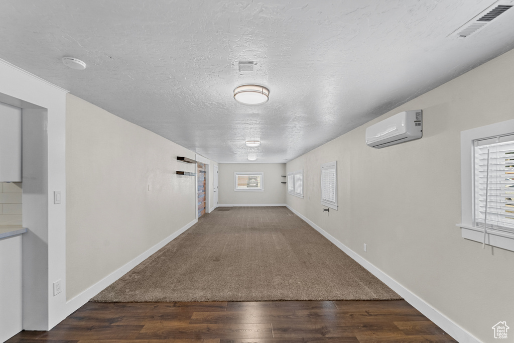 Interior space with wood-type flooring, a textured ceiling, and a wall mounted air conditioner