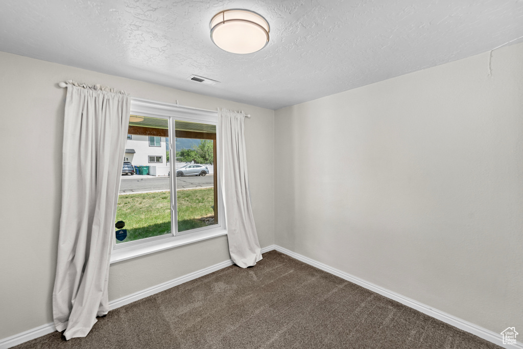 Carpeted spare room featuring a textured ceiling