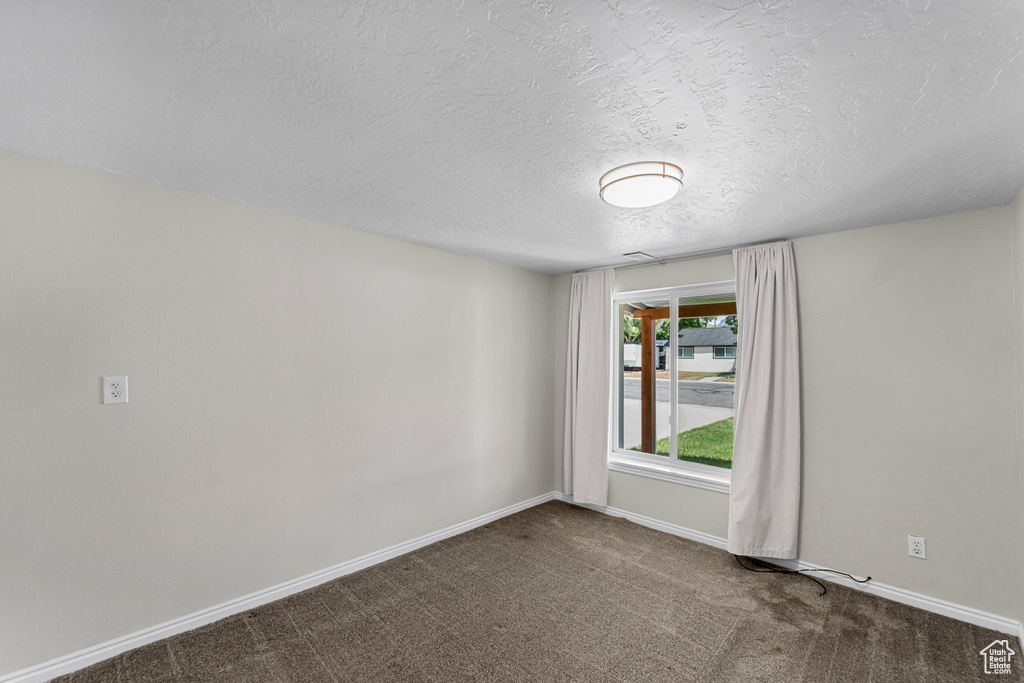 Spare room with a textured ceiling and dark carpet