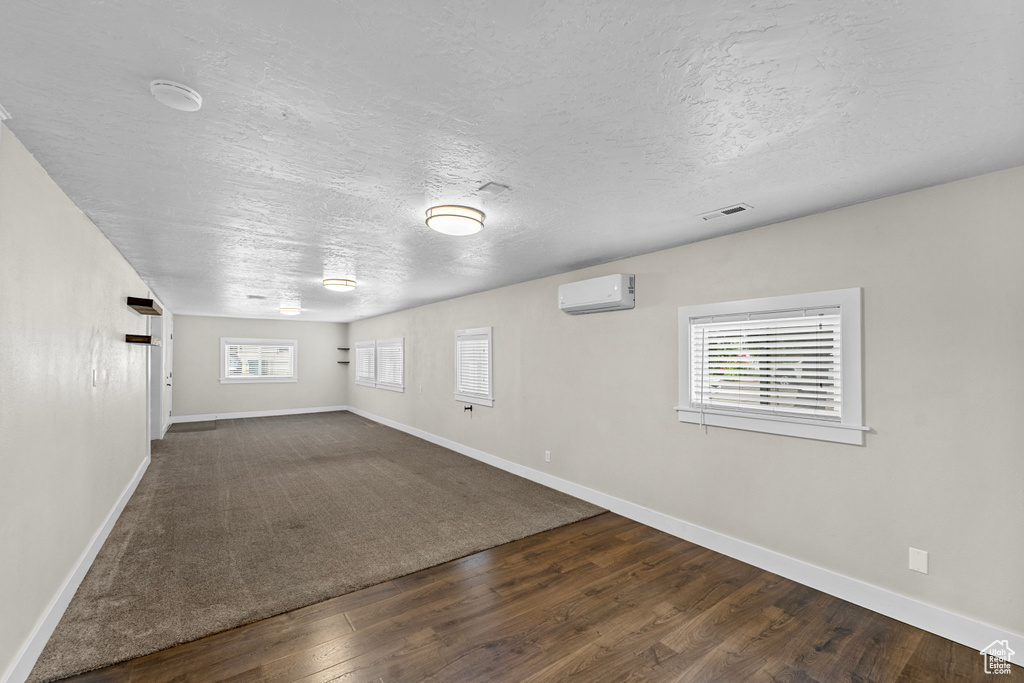 Unfurnished room with plenty of natural light, dark hardwood / wood-style flooring, and a wall mounted air conditioner