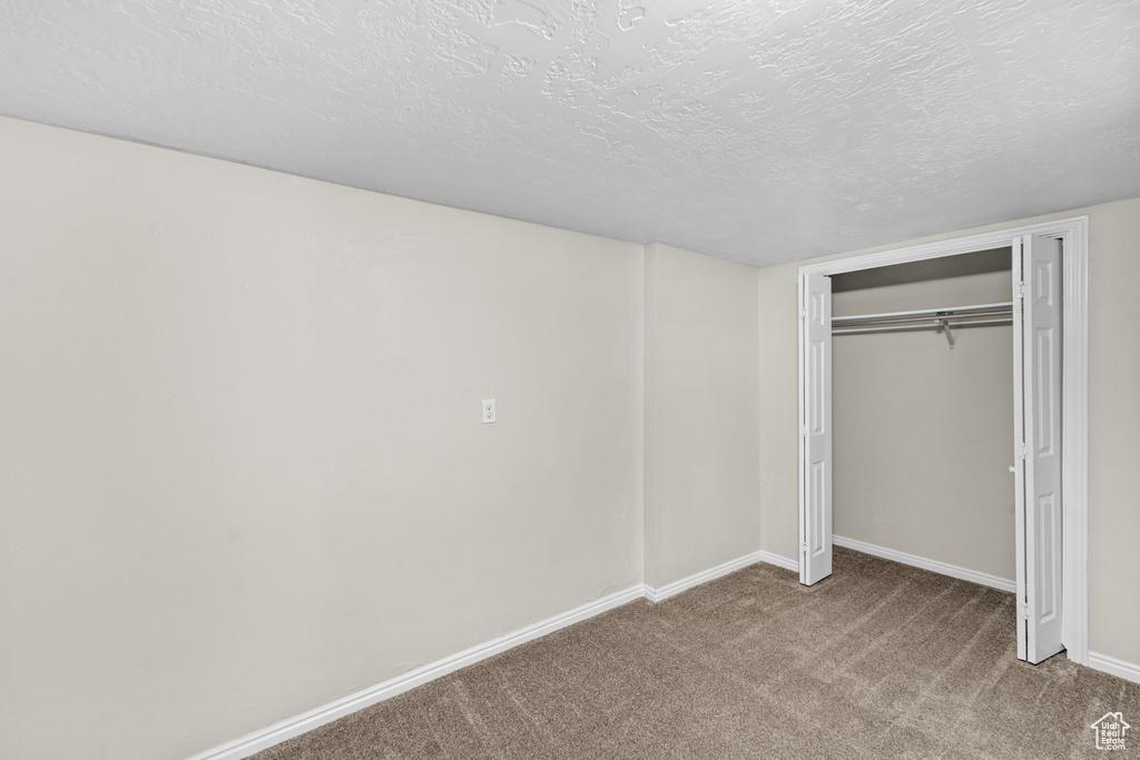 Unfurnished bedroom with a closet, a textured ceiling, and carpet floors