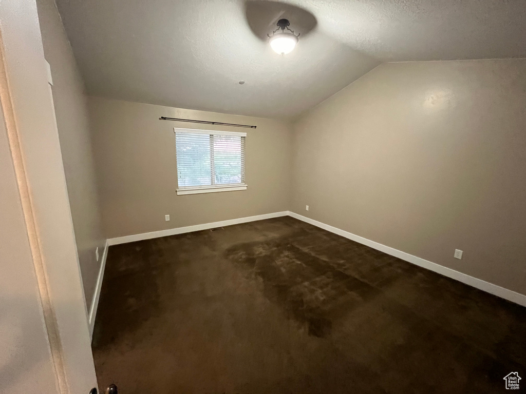 Carpeted spare room with a textured ceiling and lofted ceiling