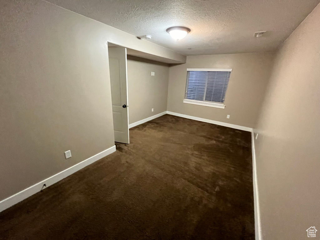 Spare room with dark colored carpet and a textured ceiling