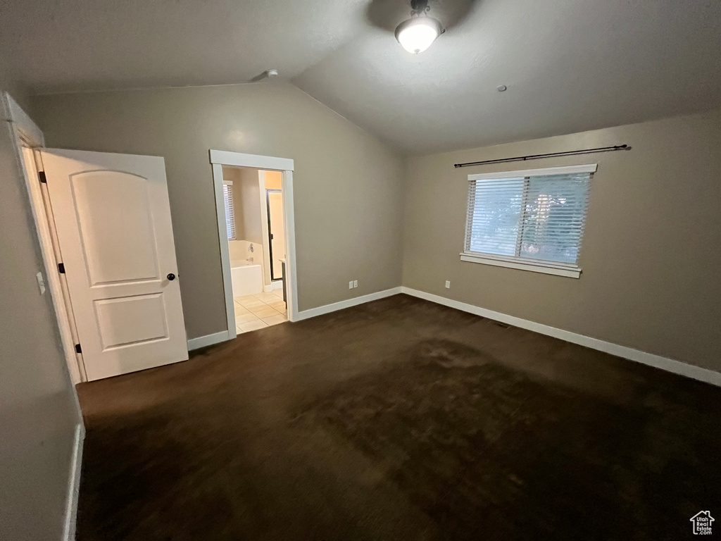 Unfurnished bedroom with tile flooring, vaulted ceiling, and ensuite bath