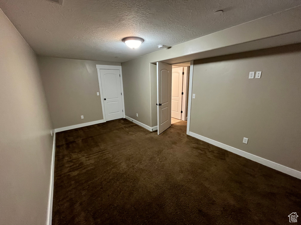 Basement with dark colored carpet and a textured ceiling