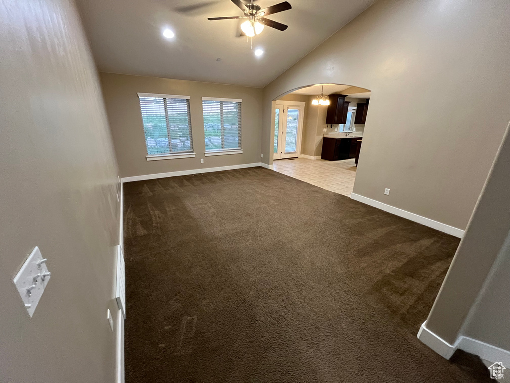 Unfurnished living room with carpet flooring, ceiling fan, and vaulted ceiling