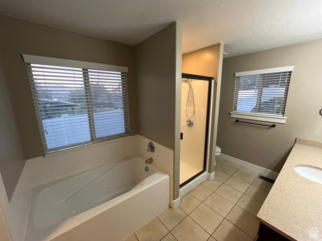 Full bathroom featuring separate shower and tub, a textured ceiling, tile floors, toilet, and vanity