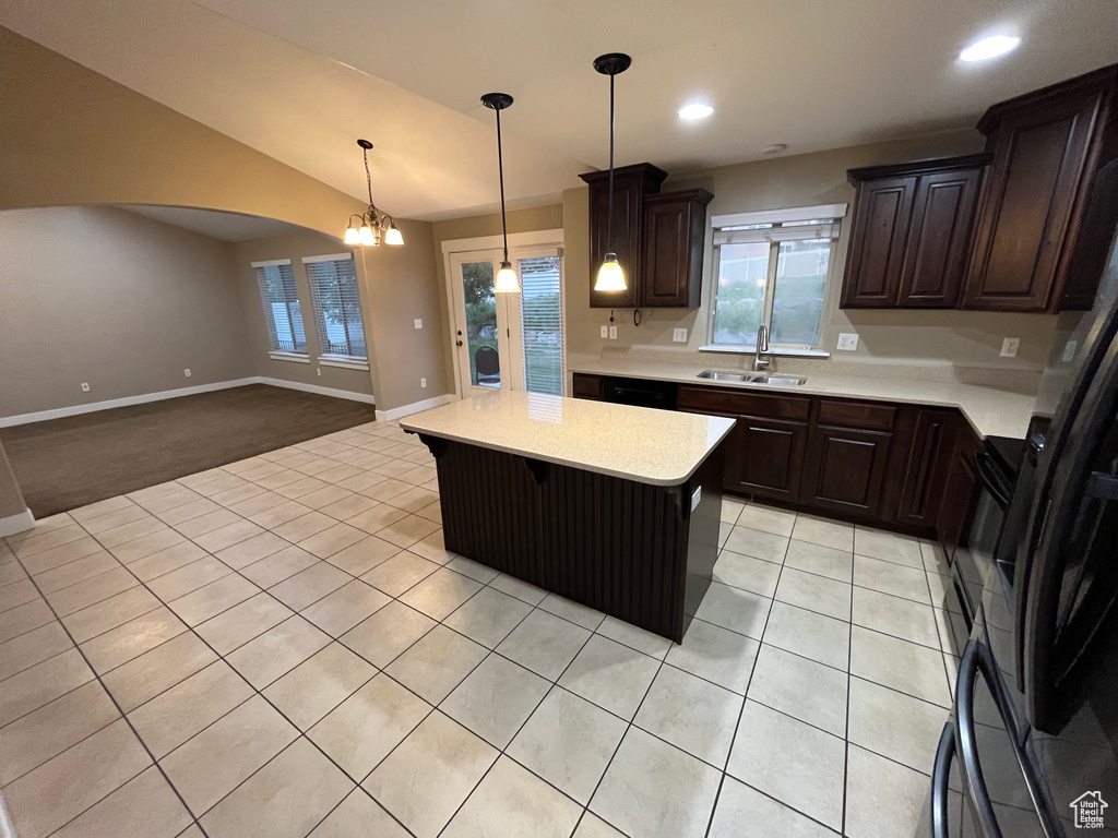 Kitchen with hanging light fixtures, dark brown cabinets, a notable chandelier, sink, and light colored carpet