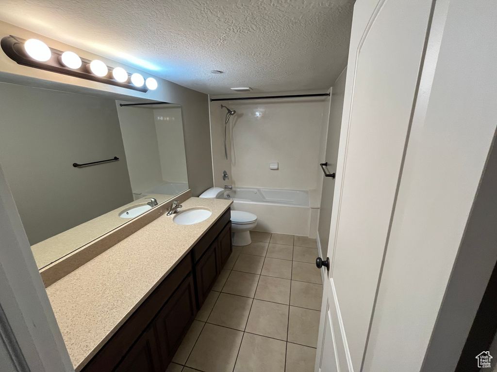 Full bathroom with toilet, bathtub / shower combination, tile flooring, vanity, and a textured ceiling