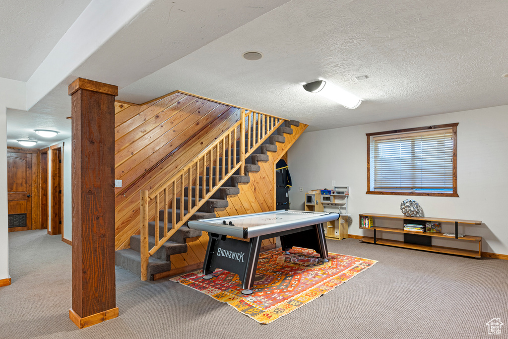 Playroom featuring decorative columns, a textured ceiling, and carpet floors