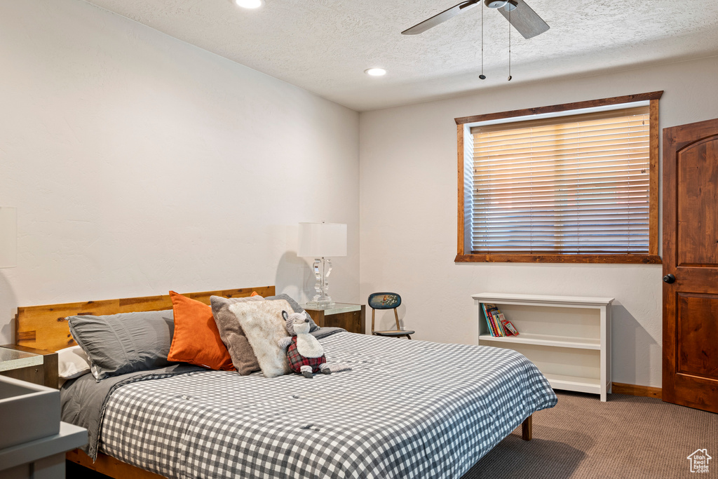 Carpeted bedroom featuring ceiling fan and a textured ceiling