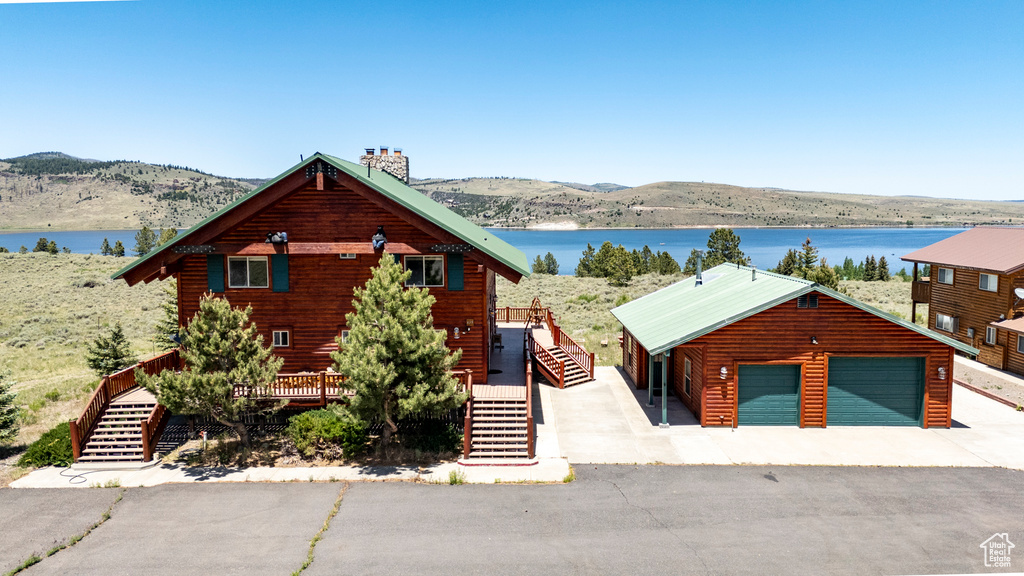 Log home with an outdoor structure, a garage, and a deck with water view