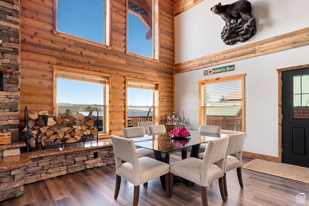 Dining space with a high ceiling, rustic walls, and hardwood / wood-style floors