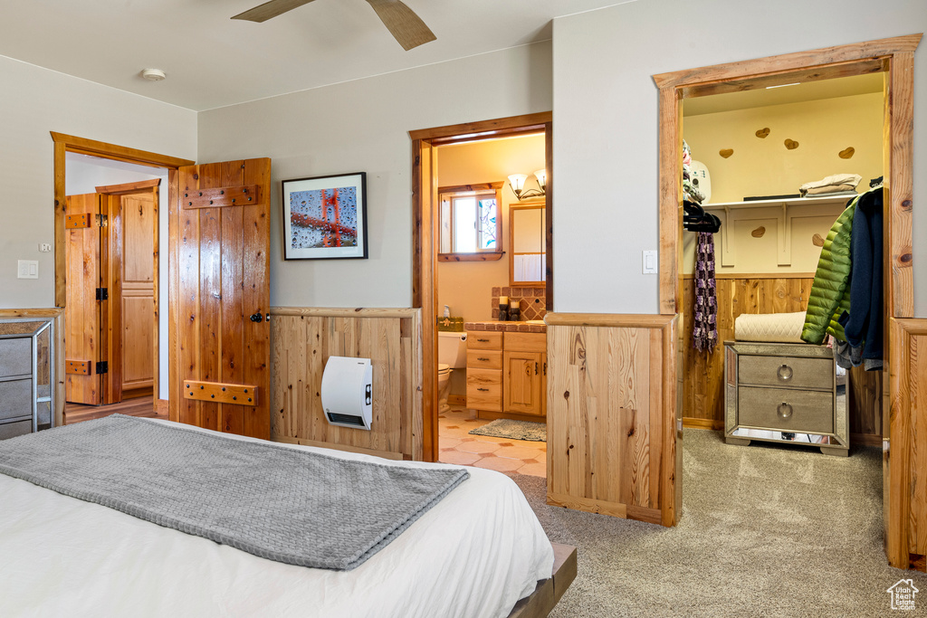 Carpeted bedroom with a walk in closet, a closet, ensuite bathroom, and ceiling fan