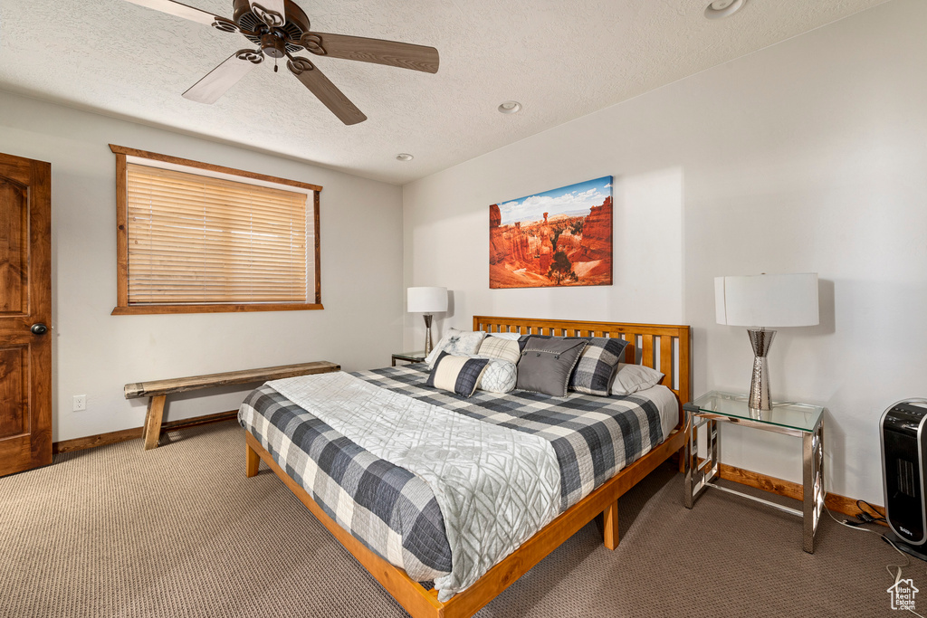 Carpeted bedroom featuring ceiling fan and a textured ceiling