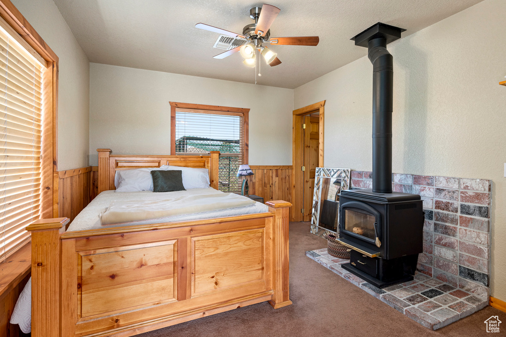 Carpeted bedroom featuring ceiling fan and a wood stove