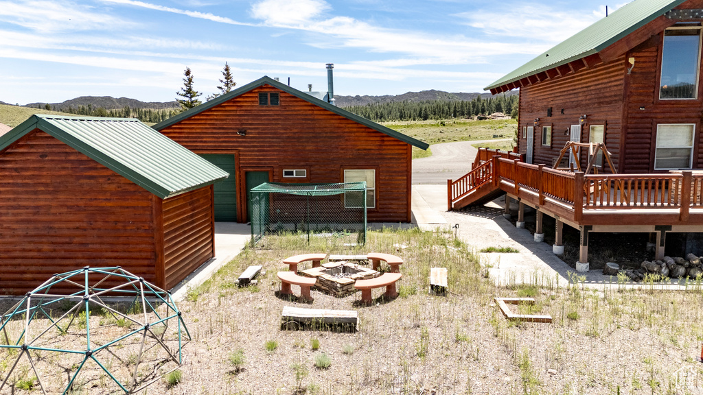 Rear view of house with a deck with mountain view and a fire pit