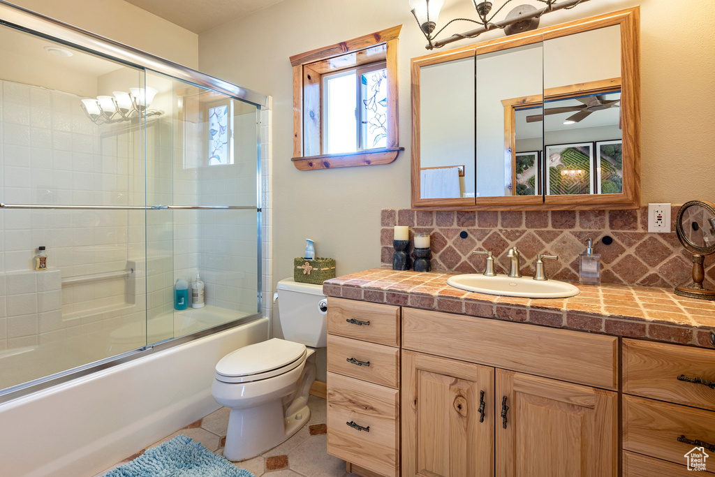 Full bathroom with backsplash, enclosed tub / shower combo, toilet, tile flooring, and vanity