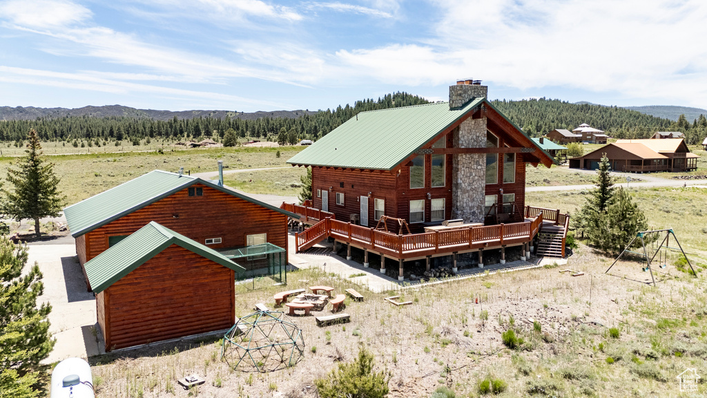 Back of property featuring a fire pit and a wooden deck