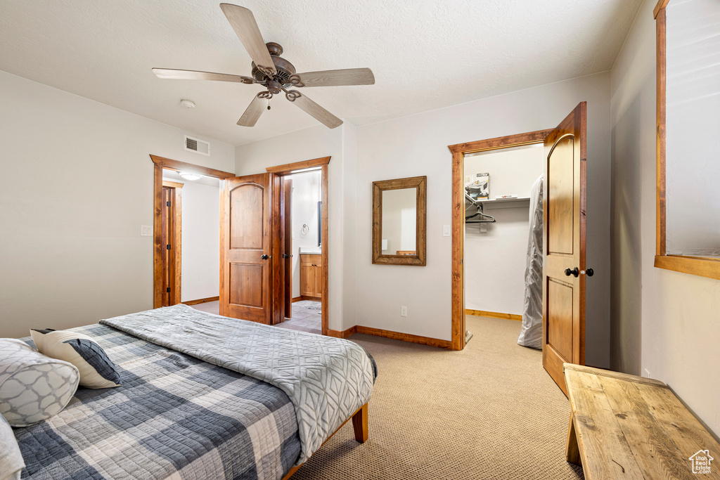 Carpeted bedroom featuring ceiling fan, a closet, and a spacious closet