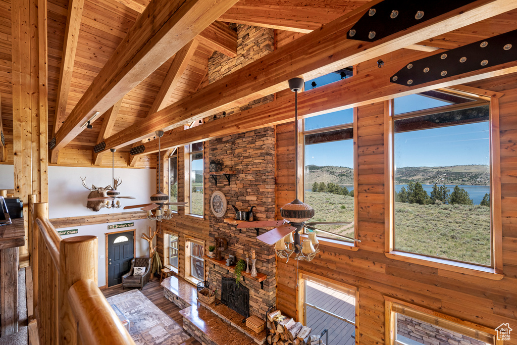 Interior space with a water view, vaulted ceiling with beams, wood walls, hardwood / wood-style flooring, and wooden ceiling