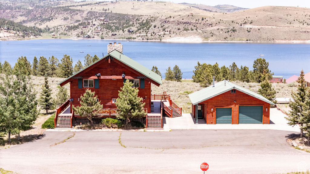 View of front facade featuring a garage, a deck with water view, and an outdoor structure