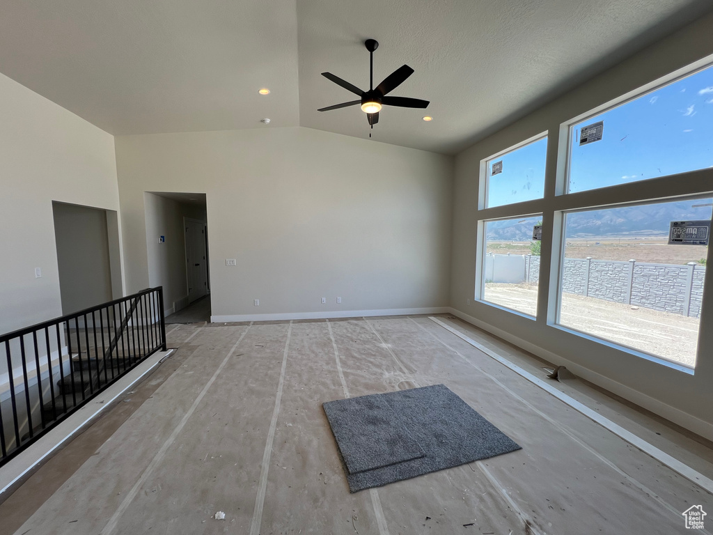 Unfurnished living room with ceiling fan and high vaulted ceiling