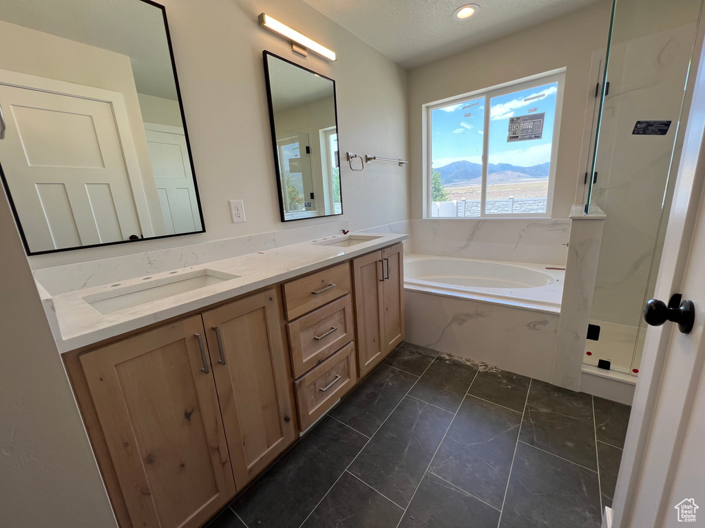 Bathroom with dual vanity, tile patterned floors, and a bathtub