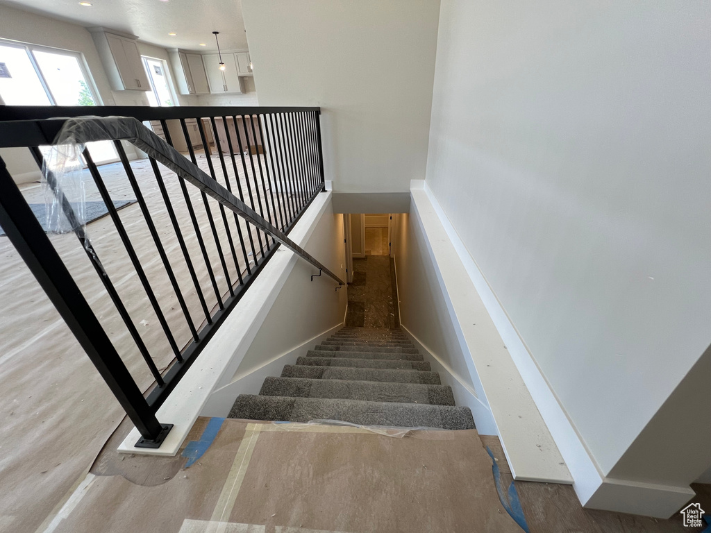 Stairway with wood-type flooring and a towering ceiling