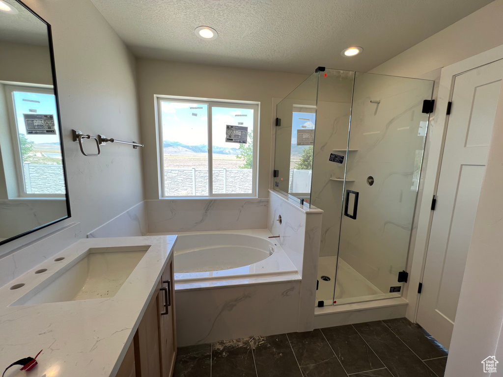 Bathroom with tile patterned floors, plus walk in shower, vanity, and a textured ceiling