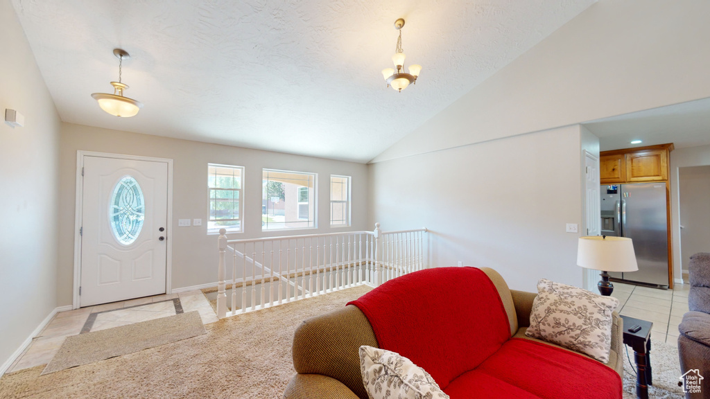 Foyer with light tile floors, a chandelier, and vaulted ceiling