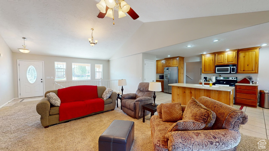 Living room featuring vaulted ceiling, sink, light tile floors, and ceiling fan with notable chandelier