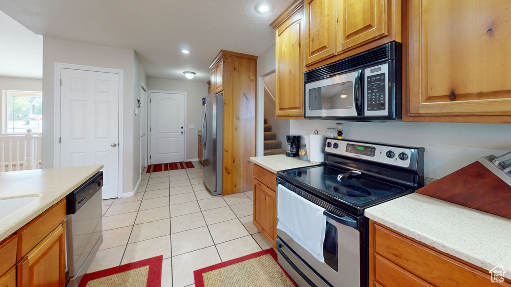 Kitchen featuring light tile floors and appliances with stainless steel finishes