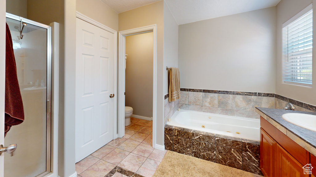 Full bathroom featuring shower with separate bathtub, tile flooring, vanity, and toilet