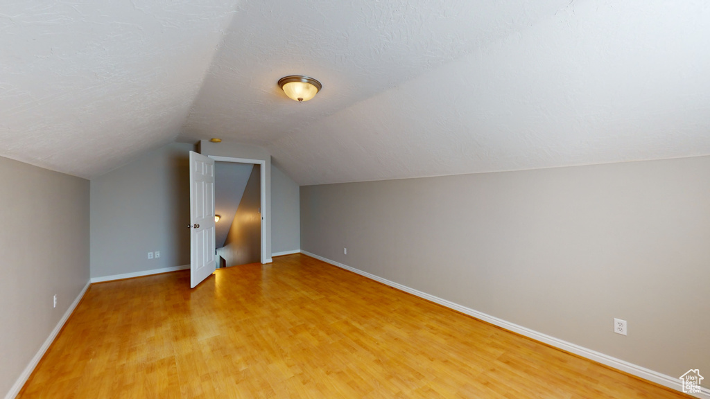 Additional living space featuring vaulted ceiling, a textured ceiling, and light wood-type flooring