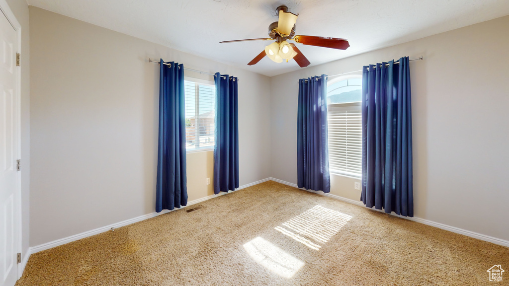 Carpeted spare room with ceiling fan