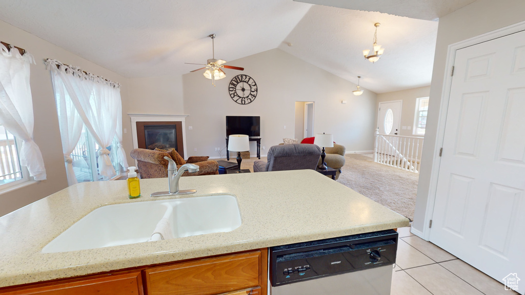 Kitchen featuring ceiling fan with notable chandelier, stainless steel dishwasher, sink, light tile floors, and lofted ceiling