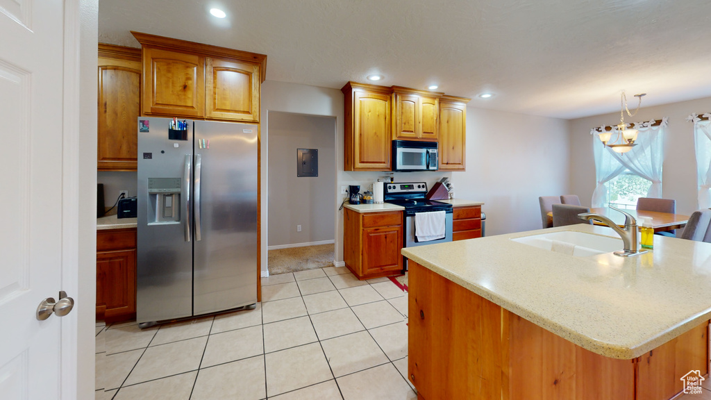 Kitchen with a kitchen island with sink, appliances with stainless steel finishes, sink, light tile floors, and pendant lighting