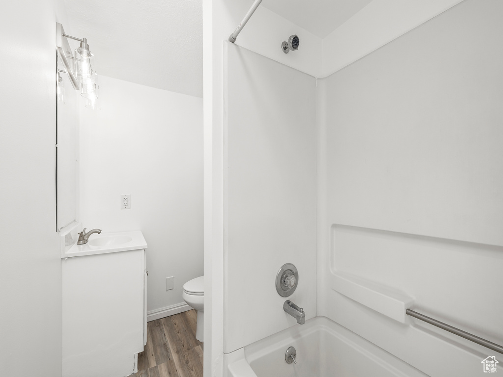 Full bathroom featuring shower / bath combination, hardwood / wood-style flooring, toilet, and vanity