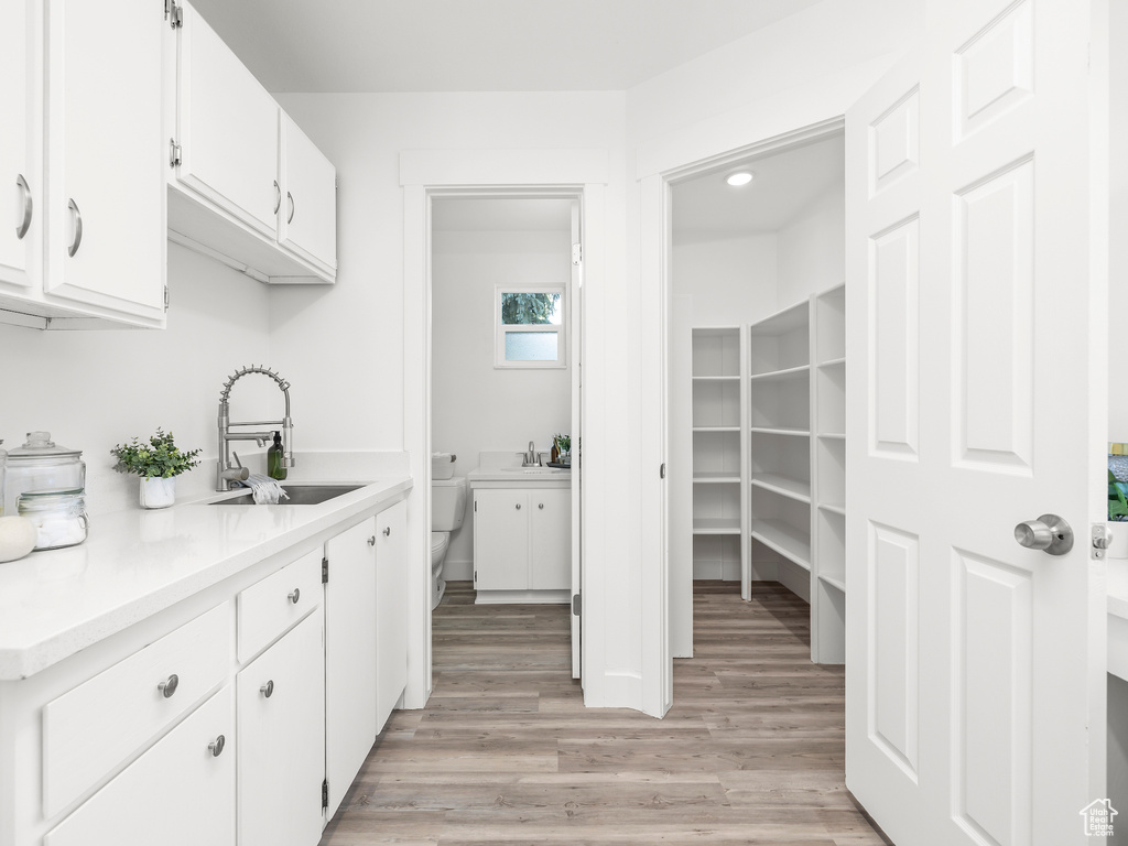 Kitchen with sink, light hardwood / wood-style flooring, and white cabinets