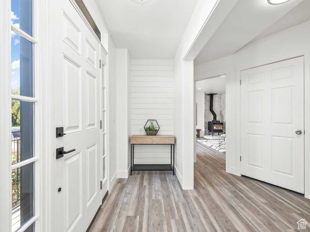 Foyer entrance with light hardwood / wood-style floors, wood walls, and a wood stove