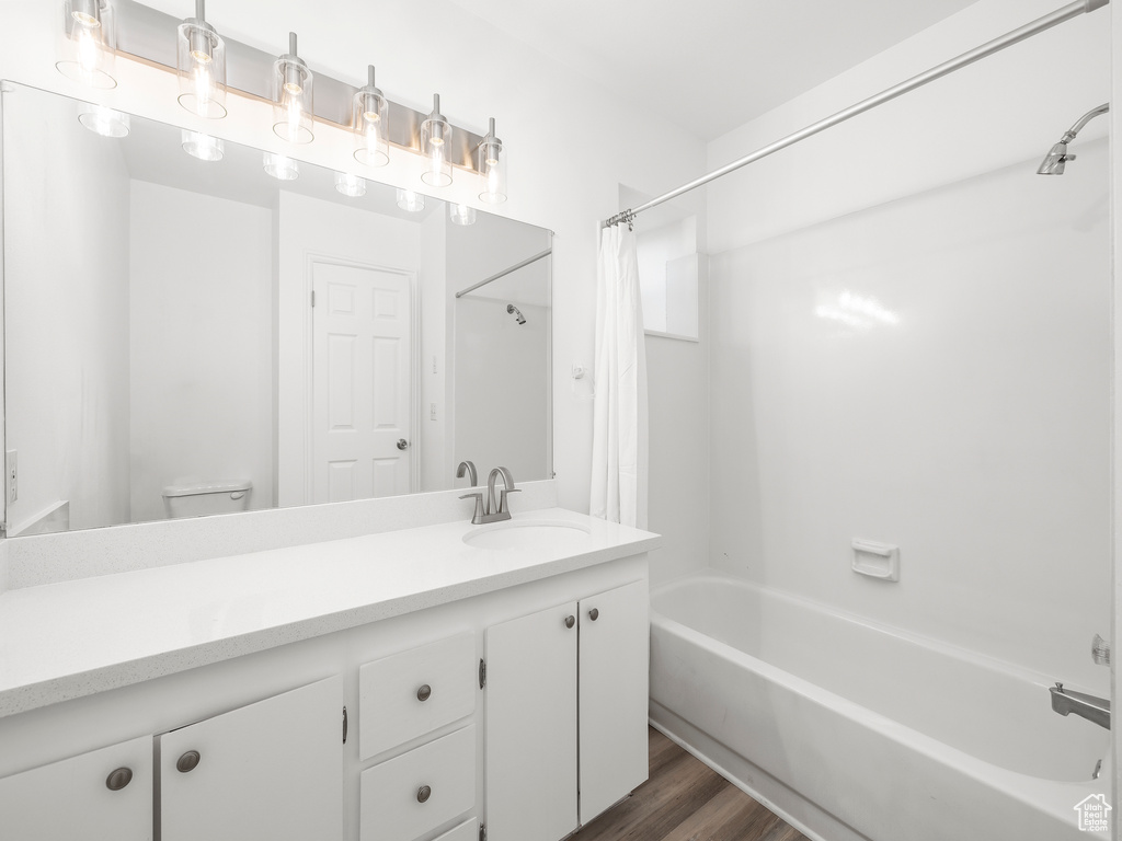 Full bathroom featuring wood-type flooring, shower / tub combo, toilet, and vanity