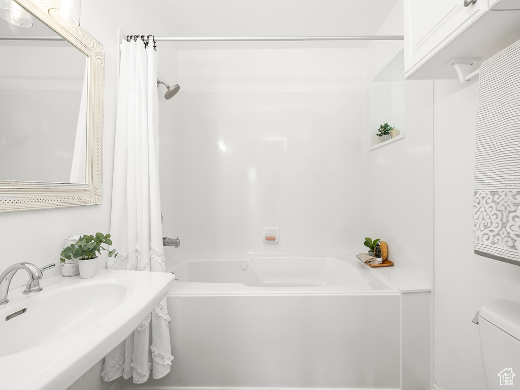 Full bathroom with sink, toilet, and shower / bath combo with shower curtain