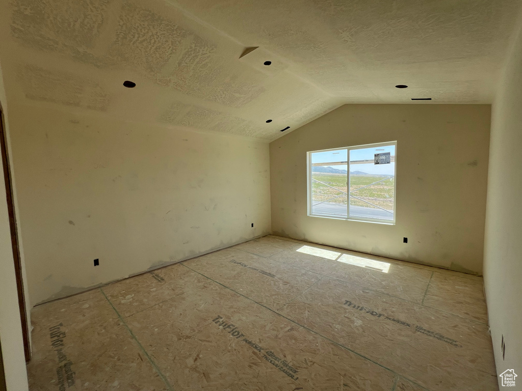 Additional living space with a textured ceiling and lofted ceiling