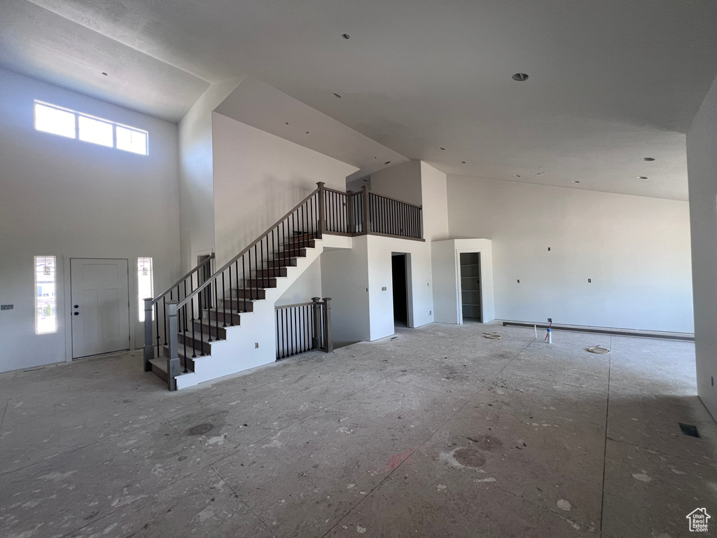 Unfurnished living room featuring plenty of natural light and a towering ceiling