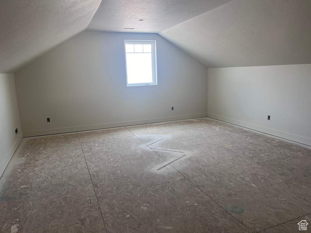 Bonus room with a textured ceiling and lofted ceiling