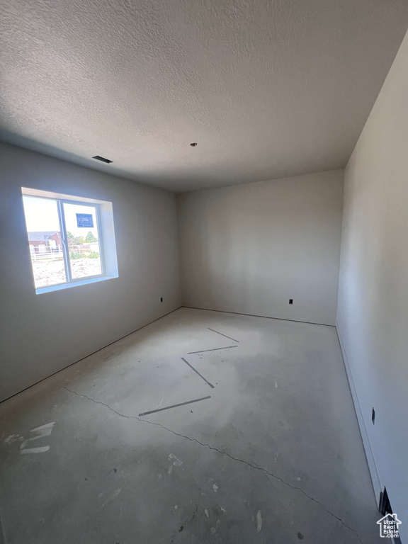 Spare room featuring a textured ceiling and concrete flooring