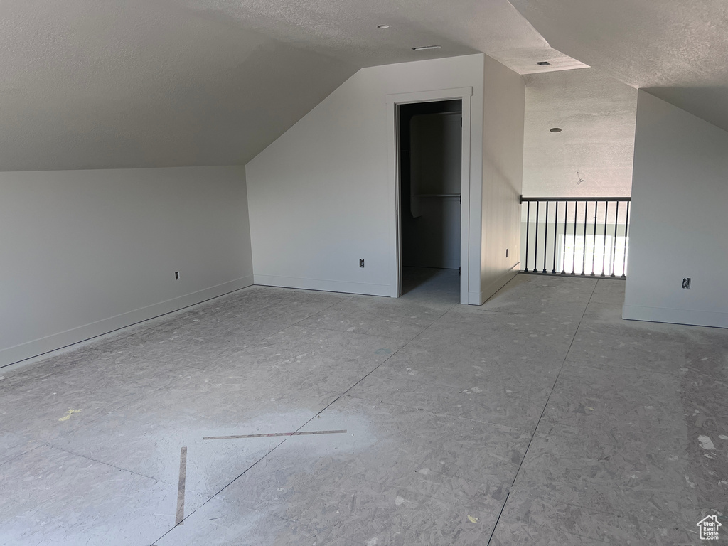 Additional living space with a textured ceiling and lofted ceiling