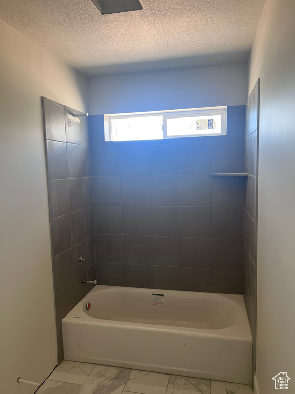 Bathroom featuring tile floors, tiled shower / bath, and a textured ceiling